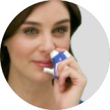 Woman using application device ONZETRA® Xsail® (sumatriptan nasal powder)